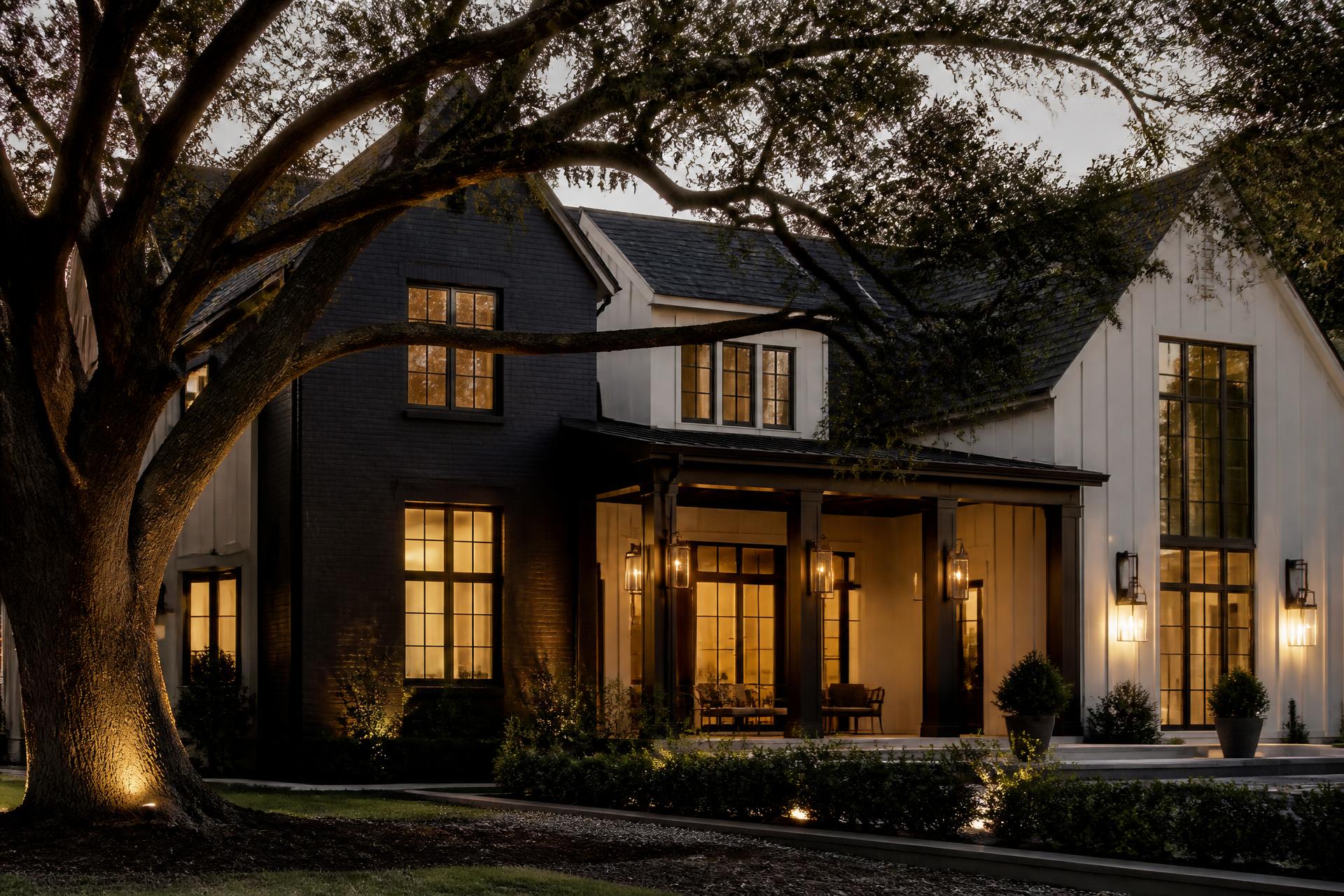 Renovated Southern residence at dusk with a deep covered porch and warm interior light